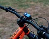 Close-up of a bicycle's handlebars and front fork, with a blue accessory mounted on the handlebars. Voir les images du produit