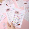 A collection of face gem sticker sheets, with a hand holding two of the sheets. Produktbild-Vorschau