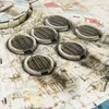 A close-up view of several circular, metallic puzzle pieces with a ribbed pattern, resting on a detailed, textured surface that appears to be part of a larger model or puzzle. Anteprima dell’immagine prodotto