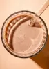 A close-up overhead view of a glass of chocolate milk with a straw. Produktbild-Vorschau