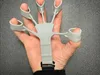 A hand wearing a finger exerciser device. Náhled obrázku produktu