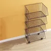 A wire rack shelving unit with three baskets is placed against a yellow wall and a white baseboard. Anteprima dell’immagine prodotto