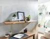 A wooden shelf with decorative items and books above a desk with a notebook and pens. Náhled obrázku produktu