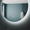 A round bathroom mirror with LED lighting is shown reflecting a teal wall with a bathrobe hanging on a hook. Anteprima dell’immagine prodotto
