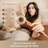 A woman is holding a hairdryer while sitting on a couch, with text overlays describing the product's features. Produktbild-Vorschau