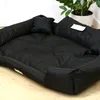 A black dog bed is shown on a light wooden floor with a potted plant in the background. Anteprima dell’immagine prodotto