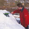 A man is clearing snow off a car windshield with a snow brush. Anteprima dell’immagine prodotto