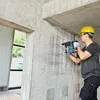 A construction worker is using a Bosch rotary hammer drill to make holes in a concrete wall. Produktbild-Vorschau