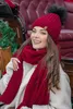 A woman wearing a red knitted hat and scarf, sitting in a carriage. Voir les images du produit