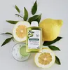 A bottle of Klorane shampoo is displayed with citrus fruits and leaves. Podgląd zdjęcia produktu