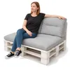 A woman is sitting on a pallet sofa with cushions. Náhled obrázku produktu
