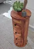 A round wooden side table with drawers sits on a textured rug. Voir les images du produit