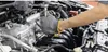 A person wearing gloves is working on a car engine. Produktbild-Vorschau