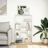 A white bookshelf filled with books, plants, and decorative items, placed in a living room next to a sofa and a large potted plant. Anteprima dell’immagine prodotto