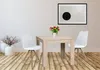 A dining table with two chairs, set in a room with a wooden floor and a framed picture on the wall. Anteprima dell’immagine prodotto