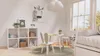 A child's bedroom with a white cube shelf, a small table and chairs, and a bed. Produktbild-Vorschau