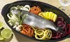 A whole fish and spiralized vegetables are arranged in a black oval baking dish, with lime wedges on the side. Produktbild-Vorschau