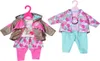 Two outfits for a baby doll are displayed on hangers against a white background. Podgląd zdjęcia produktu