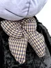 A close-up view of a large black teddy bear's chest area, featuring a plaid bow. Podgląd zdjęcia produktu
