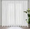 A white sheer curtain with a subtle pattern hangs in front of a window. Produktbild-Vorschau
