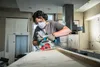 A person wearing safety gear is using a circular saw to cut a piece of wood in what appears to be a kitchen renovation. Produktbild-Vorschau