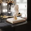A vanity table with makeup brushes, books, and a bust sculpture. Produktbild-Vorschau