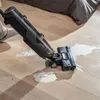 A person is using a vacuum cleaner to clean up a spill on a wooden floor. Voir les images du produit
