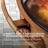 Close-up of a fire pit handle and the top edge of the fire pit with flames visible inside. Produktbild-Vorschau