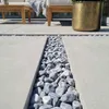 Blaugrau gemaserte Kieselsteine als dekorativer Streifen zwischen großformatigen Terrassenplatten Produktbild-Vorschau