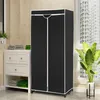 A black portable wardrobe with white trim stands next to a window and a white cabinet filled with folded towels and plants. Podgląd zdjęcia produktu