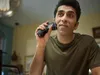 A man is shaving his face with an electric shaver in a room. Produktbild-Vorschau