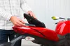A person is placing a black object onto the red seat of a red Ducati motorcycle. Náhľad obrázku produktu