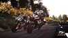 Two motorcycle racers on a road, with trees and foliage in the background. Náhled obrázku produktu