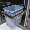 A close-up view of a gray plastic bin with handles, mounted on a metal sliding mechanism, likely part of a kitchen or outdoor setup. Náhled obrázku produktu