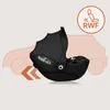 A black baby car seat is shown in profile, with a stylized outline of a car in the background. There are orange arrows indicating movement. Produktbild-Vorschau