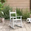 A white wooden rocking chair sits on a paved patio in a garden setting, with plants and a wooden fence in the background. A soccer ball is visible to the right of the chair. Náhľad obrázku produktu