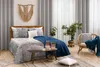 A bedroom scene with a bed, chair, and plants. Produktbild-Vorschau