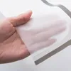 A hand holding a translucent material, possibly a shower curtain, against a plain background with gray stripes. Produktbild-Vorschau