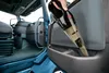A hand is using a black and transparent handheld vacuum cleaner to clean the interior of a truck. Podgląd zdjęcia produktu