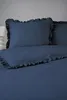 A close-up view of a dark blue duvet cover and pillowcase with ruffled edges, laid out on a bed. Anteprima dell’immagine prodotto