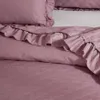A close-up view of a pink quilted bedspread with ruffles. Produktbild-Vorschau