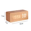 A digital alarm clock with a wooden casing is shown against a white background, with dimensions indicated by lines and text. Produktbild-Vorschau