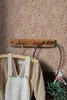 A close-up shot of children's clothing hanging on a wooden rack against a floral wallpaper. Podgląd zdjęcia produktu