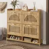 A wooden shoe cabinet with four doors and open shelves, decorated with a handbag and a vase of flowers on top, placed in a home entryway. Voir les images du produit