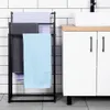 A black metal towel rack with three towels hanging on it, placed next to a white bathroom vanity with a wooden countertop. Náhľad obrázku produktu