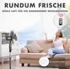 A woman is relaxing on a couch while a fan circulates air in a living room. The fan is on a stand and appears to be adjustable in height. A remote control is shown in a circular graphic, indicating remote operation. A graphic also indicates quiet operation Produktbild-Vorschau