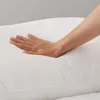 A hand pressing down on a white pillow. Produktbild-Vorschau
