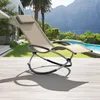 A rocking lounge chair is placed on a wooden deck next to a swimming pool, with a house and mountains in the background. Voir les images du produit