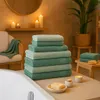 A bathroom setting with towels, candles, and a plant. Produktbild-Vorschau