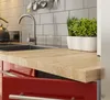 A close-up view of a red kitchen cabinet with a wooden countertop and a plant. Náhľad obrázku produktu